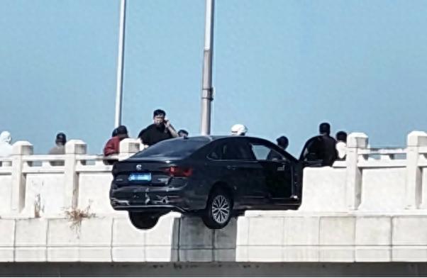 轿车撞断大桥护栏悬空中 过路男子冲上前压住车头